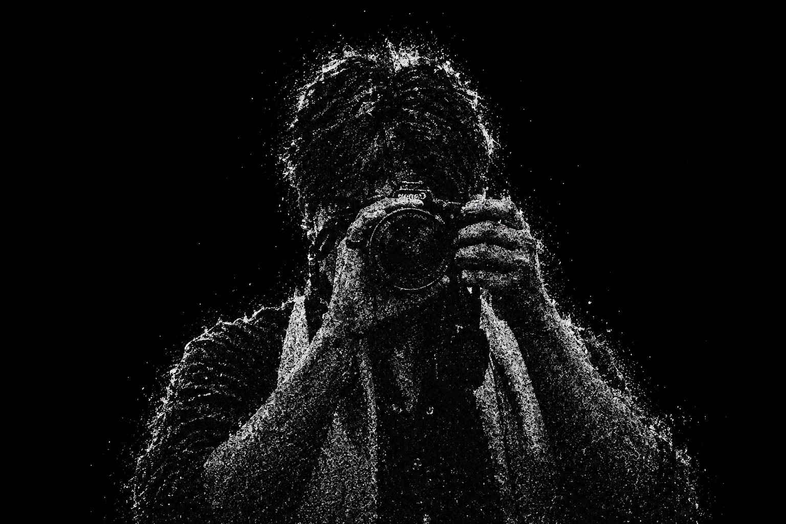 Self-portrait of Fahad in grainy black and white, face hidden behind a camera, hands gripping it